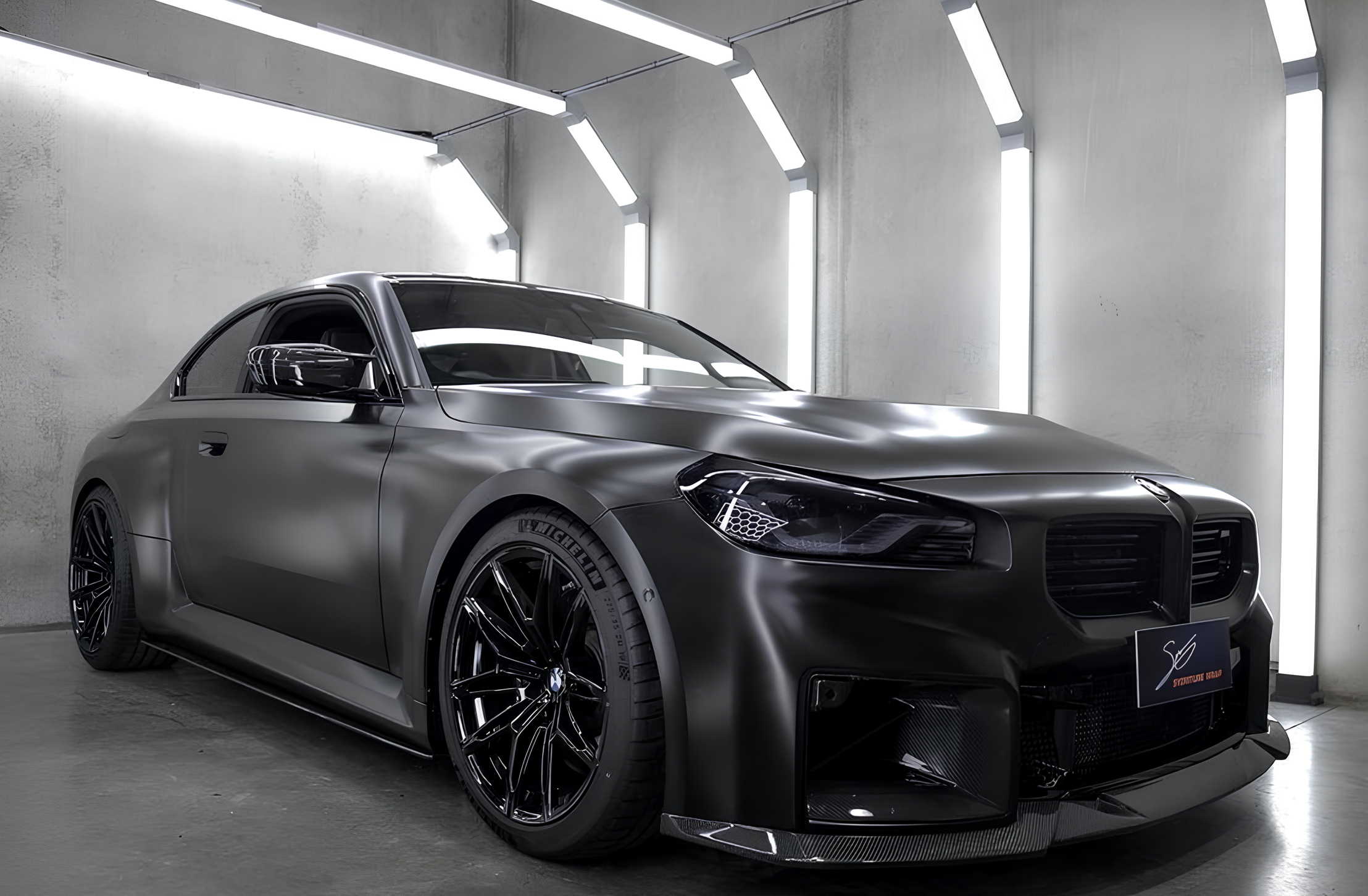 Covering noir satiné sur une BMW M2 coupé, photographiée en studio sous des rampes lumineuses